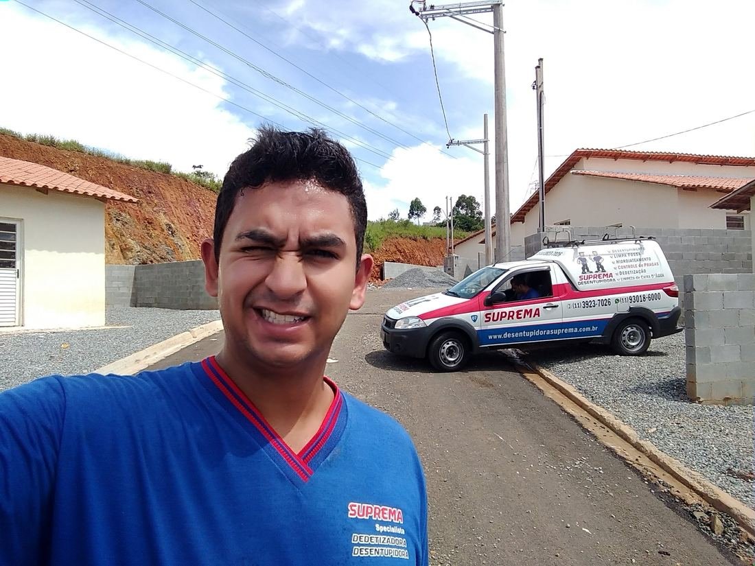 Técnico da Suprema Desentupidora ao lado do veículo de atendimento — Supermercado
